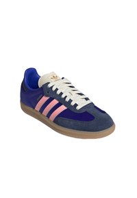 Baskets en suede bleues et violettes avec trois rayures roses, lacets crème et semelle en caoutchouc beige. Le logo sur la languette indique "adidas samba."