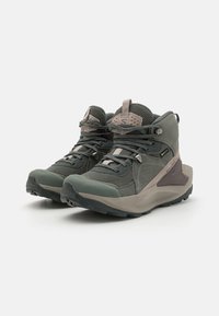 Braune und grüne Wanderschuhe mit oberer Schicht aus strukturiertem Mesh, verstärkter Zehenpartie, Gummisohle und kontrastierenden beigen Akzenten.