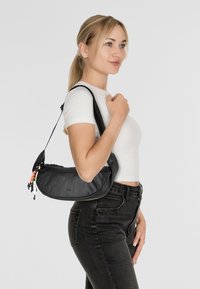 Black synthetic shoulder bag with a curved design, featuring colorful zipper pulls and an adjustable strap. Smooth texture, minimalist style.
