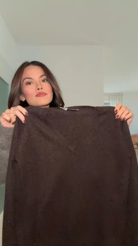 Brauner, strukturierter Pullover mit V-Ausschnitt und Reißverschluss. Der Stoff wirkt weich und dick, geeignet für kälteres Wetter.