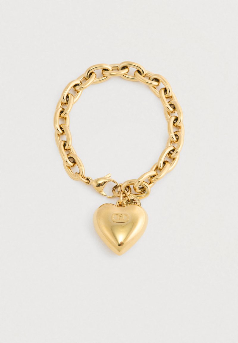 Χρυσή αλυσίδα βραχιόλι με περλίτσα σε σχήμα καρδιάς και μικρή στρογγυλή γοητεία, σε απλό φωτεινό φόντο.