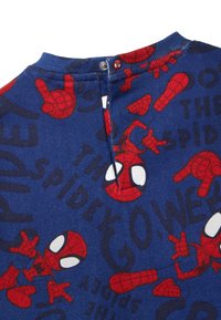 Blauwe stof met rode Spider-Man graphics en tekst. Ronde halslijn met drukknoopsluiting aan de achterkant voor gemakkelijk aan- en uittrekken. Zachte textuur.