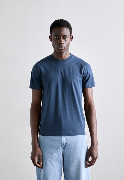Marineblaue Baumwoll-T-Shirt mit kurzen Ärmeln, Rundhalsausschnitt und glatter Textur; kombiniert mit hellblauen Denim-Jeans.