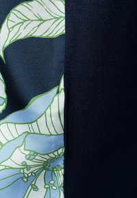 Dunkelblauem Stoff mit floralem Muster in Hellblau und Grün, der eine glatte Textur und eine gerippte Oberfläche aufweist.
