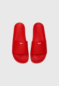 Șlapi din cauciuc roșu, cu un brâu lat și un accent mic cu logo alb. Talpă plată, textură netedă și design minimalist.