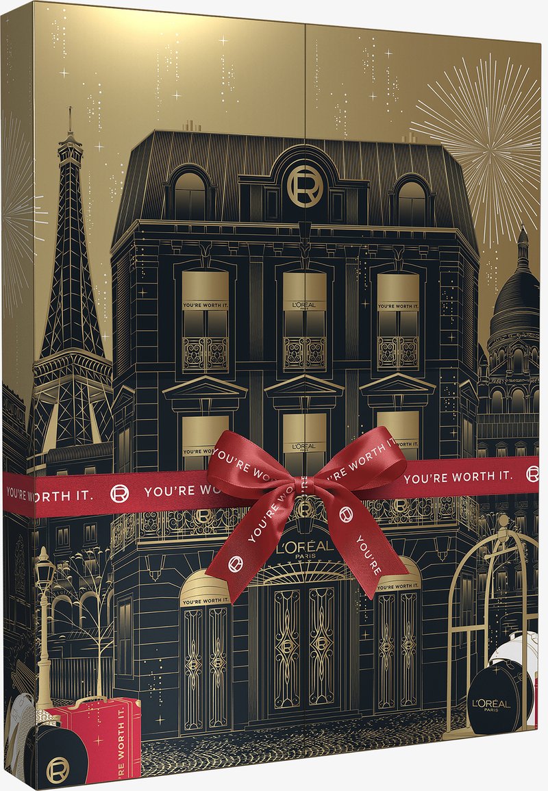Boîte-cadeau dorée et noire mettant en avant l'architecture parisienne, la Tour Eiffel et des éléments décoratifs. Ruban rouge avec le texte : "VOUS LE VALEZ BIEN."