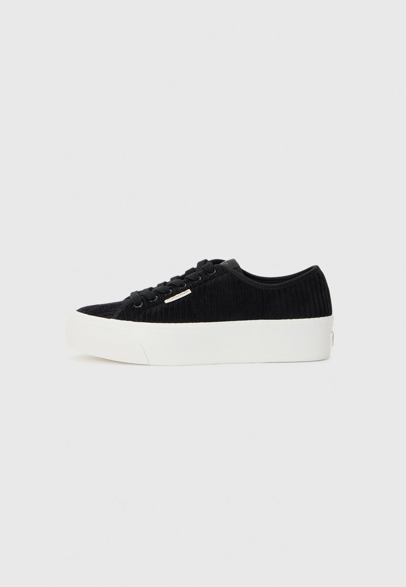 Zwarte corduroy sneaker met een witte rubberen zool. Beschikt over een ronde neus, een vetersluiting aan de voorkant en een minimale logo-accent aan de zijkant.