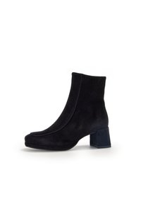 Botines de ante negro con tacón bloque, que presentan un diseño elegante, punta redonda y una textura suave que ofrece una estética minimalista.