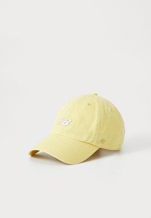 Light yellow New Balance baseball cap with curved brim and embroidered logo on front and small '47' stitching on side.