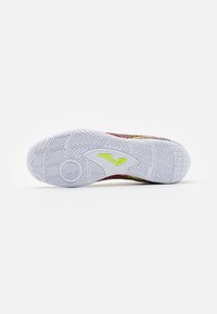 La suela del zapato presenta una base de goma blanca con patrones de relieve en zigzag y hexagonales, destacada por un logo en verde neón.