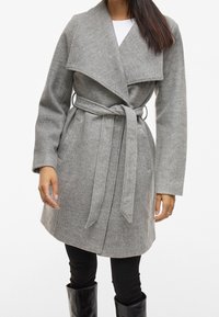 Szary wełniany płaszcz z szerokim kołnierzem, paskiem w talii, kieszeniami po bokach i długimi rękawami, o miękkiej teksturze i długości do kostek.