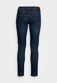 Dark blue denim jeans with a fitted shape, featuring two back pockets, a leather waistband patch, and subtle stitching details.