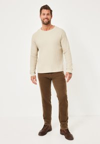 Beige waffle-knit long-sleeve shirt paired with brown corduroy pants and brown leather shoes, featuring a relaxed fit and crew neckline.