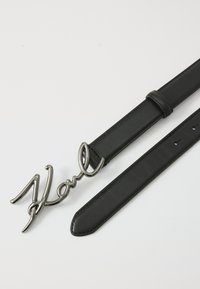 Zwarte leren riem met een metalen cursieve "Karl" gesp, een gladde textuur, een strak ontwerp en verstelbare gaatjes voor de juiste pasvorm.