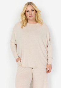 Maglia beige a maniche lunghe con una vestibilità rilassata e scollo arrotondato. Texture morbida con un sottile motivo melangiato. Tasche posizionate sui lati.