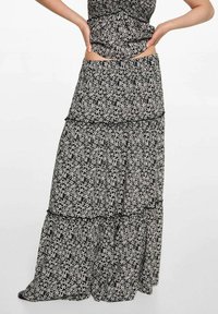 Maxiklänning i svart och vitt blommönster. Har ett lager-på-lager design, lättviktig tyg och subtila volanger längs sömmarna.