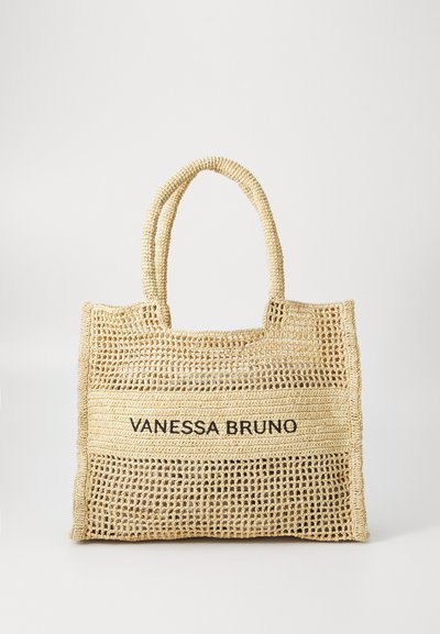 Sac fourre-tout tissé beige avec deux poignées et "VANESSA BRUNO" imprimé en noir sur un panneau tissé solide au centre.
