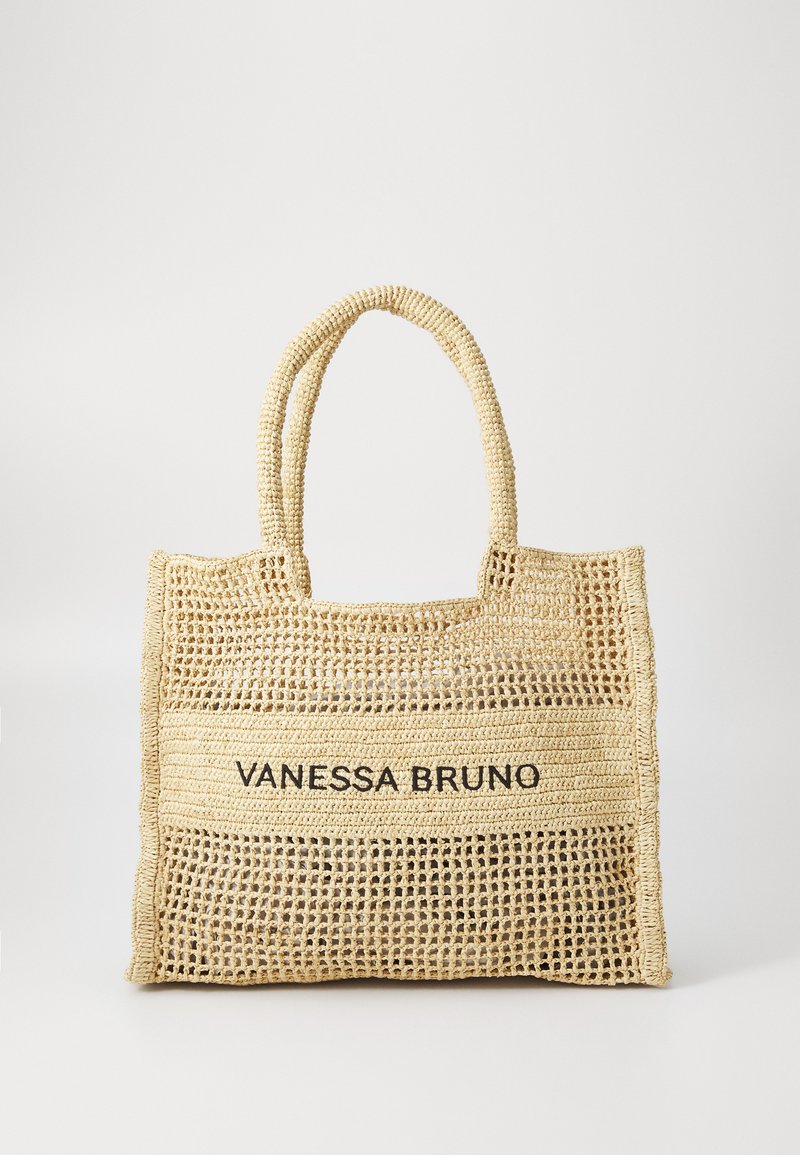 Beige kudottu käsilaukku, jossa on kaksi kahvaa ja "VANESSA BRUNO" mustana painettuna kiinteälle kudotulle paneelille keskellä.