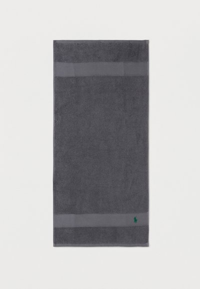 Σκούρα γκρι ορθογώνια πετσέτα με δύο υφασμένες οριζόντιες λωρίδες και μικρό πράσινο κεντητό λογότυπο στην κάτω δεξιά γωνία.