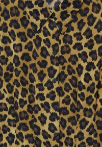 Paita kuosi leopardista ruskean ja mustan sävyissä, jossa on kaulus ja napitettava etuosa mustilla napeilla ja sileä rakenne.