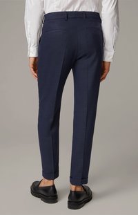 Mørkeblå skræddersyede bukser med slim fit, der har opbrugte manchetter, glat tekstur og to baglommer. Båret med sorte sko.