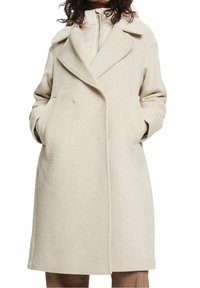 Abrigo de lana beige con cuello con muescas, cierre de doble botonadura, bolsillos frontales y un corte relajado, que llega hasta la mitad del muslo.