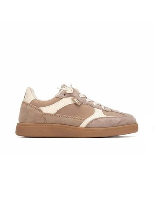 Deportiva de ante beige y marrón claro con detalles blancos, cordones y suela de goma, mostrada de perfil sobre un fondo blanco.