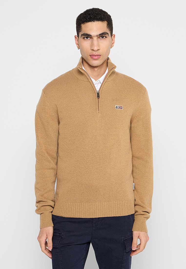 Ritssluitingtrui in lichtbruin gebreid materiaal, met een hoge kraag en rib gebreide manchetten. Klein logo patch op de borst.