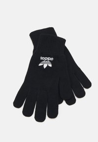 Fekete kötött kesztyű, bordás mandzsettával, az egyik kesztyűn fehér Adidas logó háromlevelű dizájnnal.