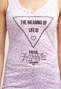 Top sin mangas de estampado de leopardo rosa con un gráfico triangular negro que contiene el texto "EL SIGNIFICADO DE LA VIDA ES" y "GUESS Los Ángeles CALIFORNIA 1981."