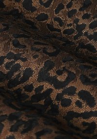 Tissu à motif animalier présentant un motif de léopard noir sur un fond texturé marron, avec une apparence lisse et tissée.