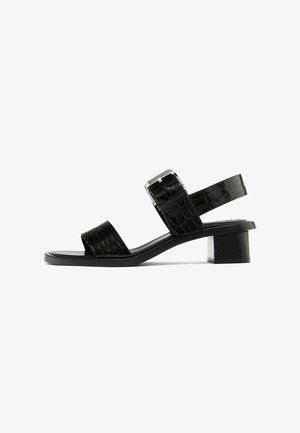 Black leather sandal with two wide straps, textured croc pattern, adjustable buckle, and a short, chunky heel.
