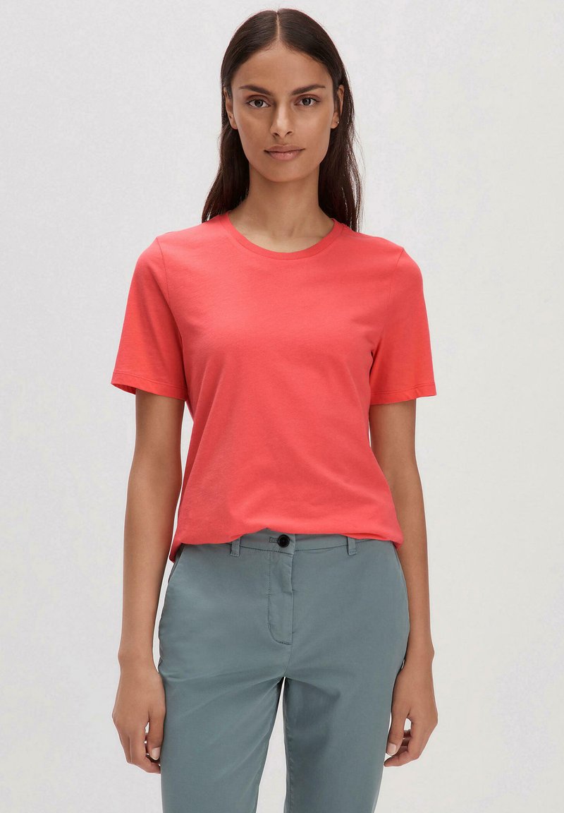 Koralli lyhythihainen t-paita, joka on valmistettu sileästä puuvillasta. Paita on pyöreäkauluksinen ja rento malli. Se on yhdistetty vaaleanvihreisiin housuihin.