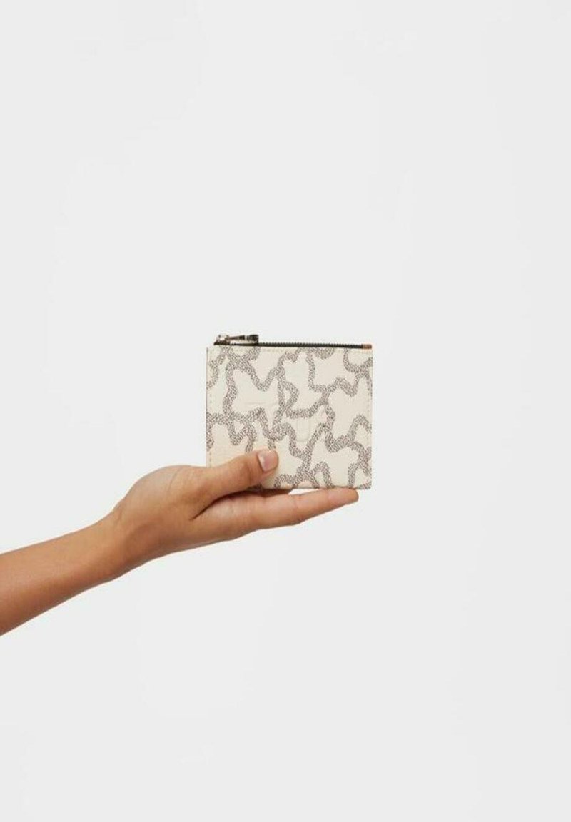 Cartera con cremallera en material blanco texturizado con un patrón abstracto negro, sostenida en una mano. Forma rectangular compacta, con un hardware mínimo.