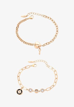 Dwie bransoletki na złotym łańcuszku: jedna z zawieszką w kształcie serca z kłódką i kluczem, druga z zawieszkami kompasu i kryształu.