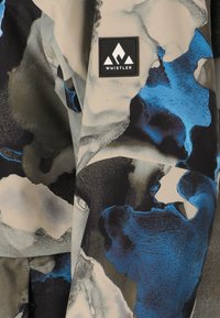 Musterstoff mit blauen, schwarzen und grauen abstrakten Designs. Enthält ein rechteckiges schwarzes Etikett, auf das "WHISTLER" gestickt ist.