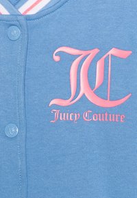 Modrá mikina s růžovým logem, které zní "Juicy Couture" a má zapínání na knoflík v světle modré barvě. Pruhovaný límec v bílé a růžové.