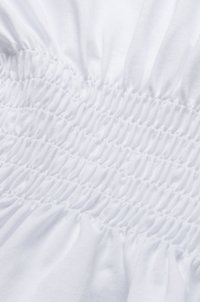 Witte stof met geplooide smockdetails, voorzien van meerdere horizontale rijen textuur, elastische stitching. Zacht, lichtgewicht materiaal.