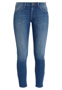 Jeans ajustados en un lavado de mezclilla azul medio, con un ligero desgastado, cinco bolsillos y un cierre de botón metálico con una etiqueta de marca en la parte trasera.