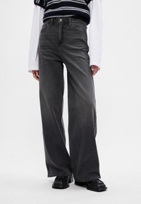 Løse sorte denimjeans med en falmet finish, høj talje, fem-lomme design og kontrastsyninger.