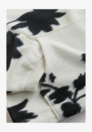 Lillemustriga villane kangas koore- ja musta värviga. Omadusteks on pehme tekstuur, nähtavad õmblused ja kerge drapeering. Disain hõlmab suuri, abstraktseid lilli.