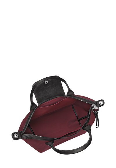 Maroon tote bag with black leather handles and interior. Features a smooth texture, zipper closure, and an inner pocket with strap detail.