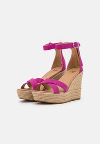 Růžové semišové sandály na klínu s překříženými pásky, opletenou podešví z juty a malým nastavitelným páskem kolem kotníku.