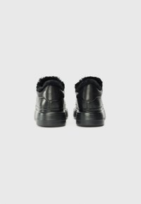 Baskets en cuir noir avec un col en fausse fourrure et une semelle épaisse et texturée. Le design est lisse avec des détails de couture subtils à l'arrière.