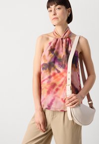 Halternecktops aus durchsichtigem, mehrfarbigem Stoff mit pinken, lila und orangefarbenen Mustern; kombiniert mit einer beigen Umhängetasche mit geschwungenem Design.