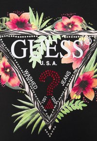 Sort t-shirt med et blomsterdesign bestående af røde og lyserøde blomster, sølv rhinsten og et trekantet Guess-logo med tekstdetaljer.