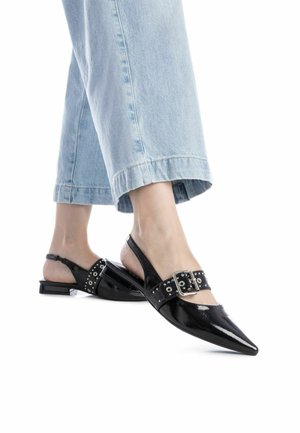 Zapatos de charol negros tipo slingback con punta afilada, que presentan una hebilla decorativa y acentos perforados en la correa. Tacón bajo de bloque.