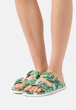 Sandaletter med blomstermotiv, der har en grøn base, dobbelte sølvspænder og en struktureret hvid sål. Åben tå-design med en bred rem.