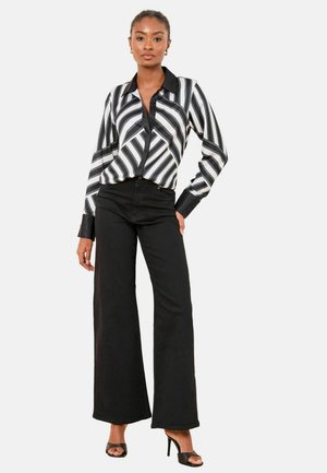 Striped button-up blouse in black and white, with a classic collar and long sleeves, paired with high-waisted black wide-leg pants.