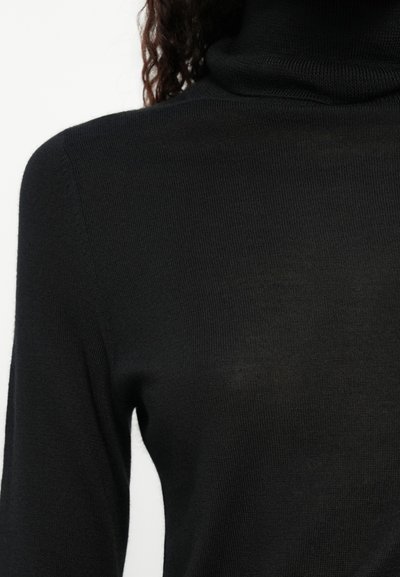Pull à col roulé noir en maille côtelée. Il présente des manches longues et une silhouette ajustée, mettant en valeur une texture lisse.